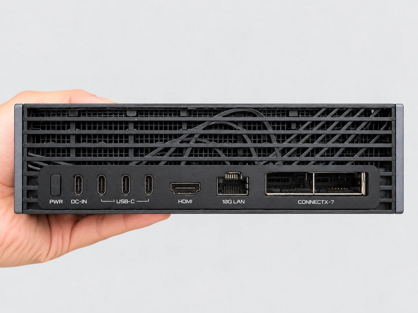 Parte traseira da AI TOP ATOM segurada na mão: botão PWR, entrada DC-IN em USB-C, três portas USB-C, uma saída HDMI, uma porta 10G LAN e as duas portas QSFP da placa ConnectX-7.